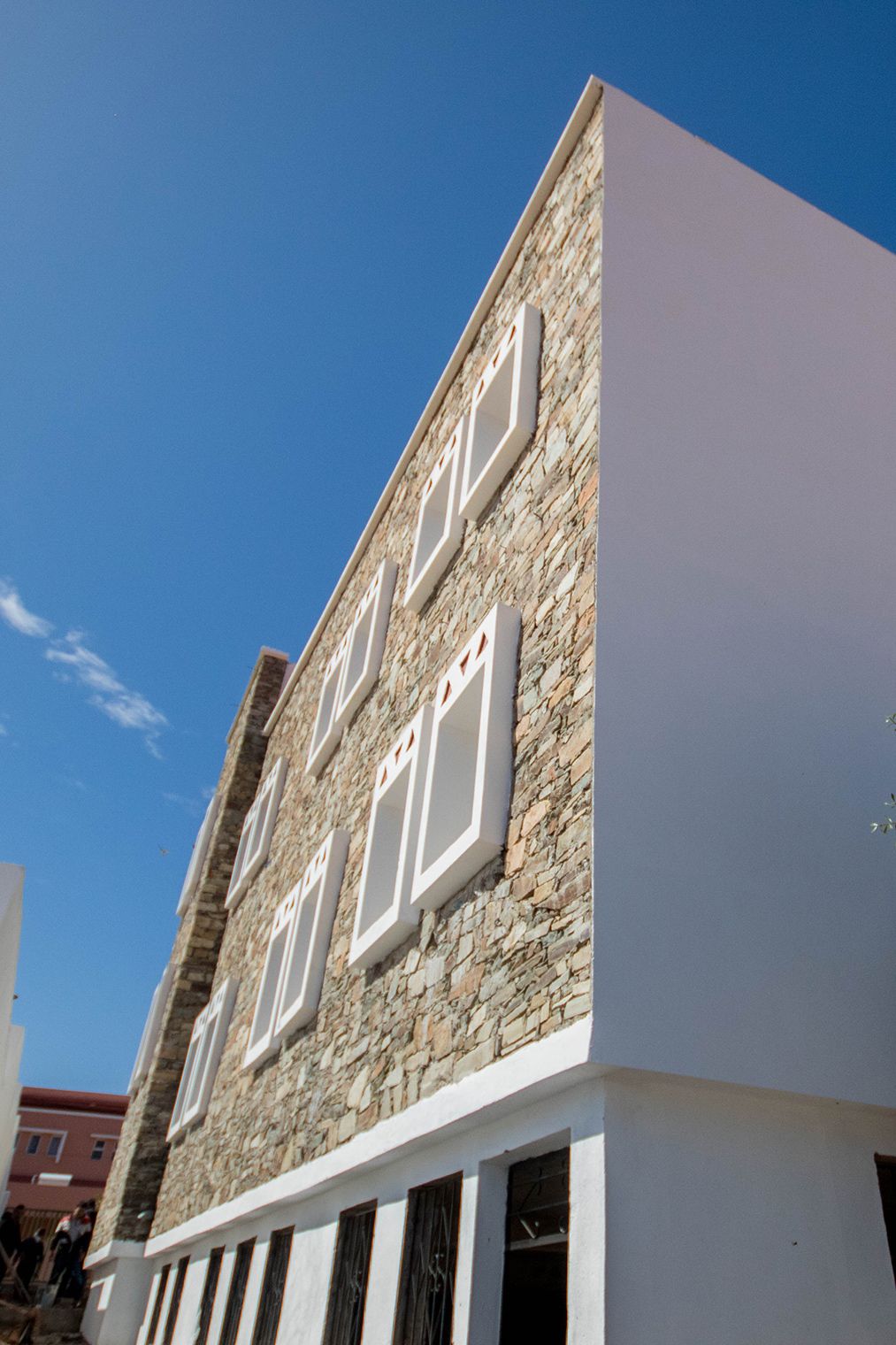 Façade en pierre et pignon blanc sous un ciel bleu